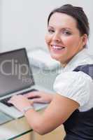 Portrait of smiling business woman using laptop at desk