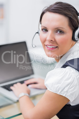 Portrait of business woman wearing headset and using laptop