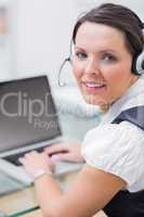 Portrait of business woman wearing headset and using laptop