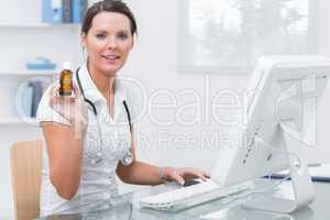 Portrait of female doctor holding medicine bottle in front of co