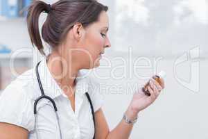 Female doctor looking at medicine bottle