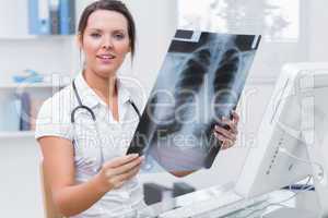 Female doctor with x-ray sitting in front of computer at clinic