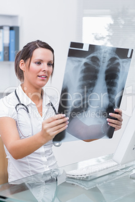 Doctor with x-ray sitting in front of computer at clinic