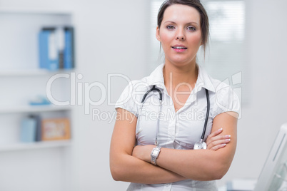 Confident female doctor with arms crossed at clinic