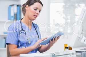 Female surgeon using digital tablet in front of computer at clin