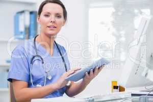 Portrait of surgeon using digital tablet in front of computer at