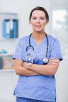 Confident female surgeon with arms crossed at clinic