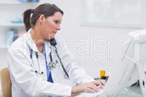 Female doctor using computer while on call at clinic