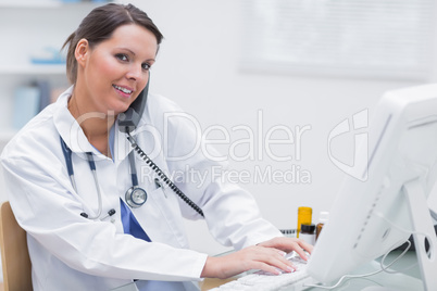 Female doctor using computer while on call at clinic