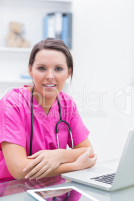 Portrait of smiling nurse with laptop at clinic