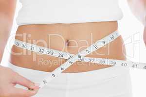 Close-up midsection of woman measuring waist