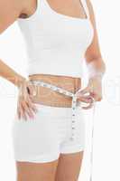 Midsection of woman measuring waist