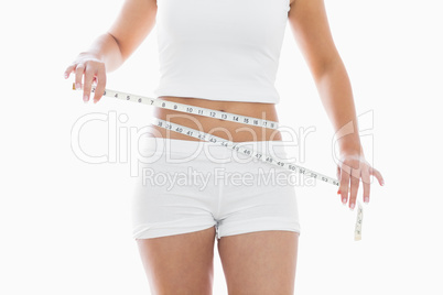 Midsection of woman measuring waist