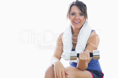 Portrait of woman sitting and exercising with dumbbell