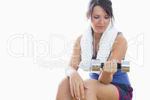 Young woman sitting and exercising with dumbbell