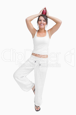 Portrait of woman doing the tree pose and holding apple