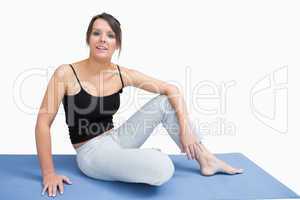 Portrait of young woman in sportswear sitting on yoga mat