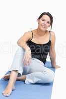 Portrait of young woman in sportswear sitting on yoga mat