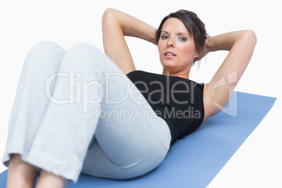 Portrait of woman doing sit-ups on exercise mat over