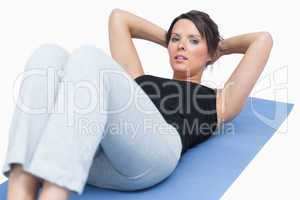 Portrait of woman doing sit-ups on exercise mat over