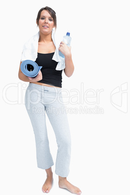 Portrait of woman in sportswear holding water bottle and mat