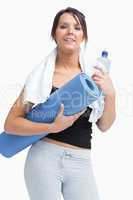 Portrait of woman in sportswear holding water bottle and mat