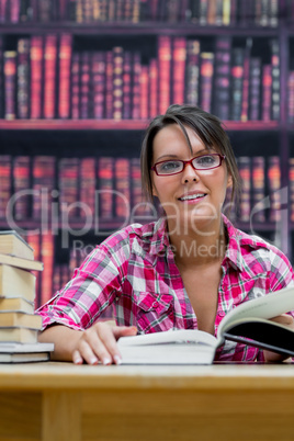 Female college student sitting with books at library