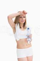 Portrait of sporty woman holding water bottle and wiping sweat w