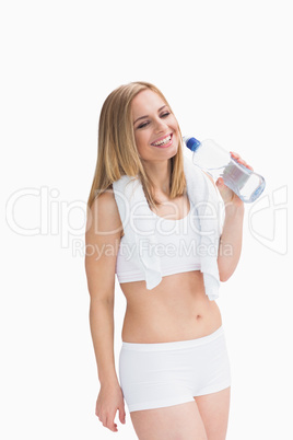 Happy young woman with towel around neck holding water bottle