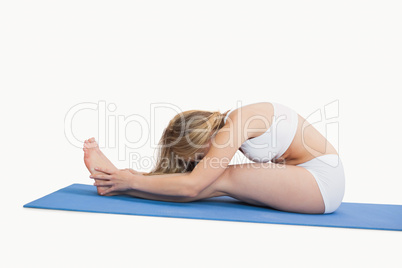 Side view of woman doing the paschimottanasana pose