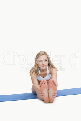 Portrait of young woman performing stretching exercise on yoga m