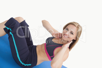 Portrait of happy young woman doing sit-ups on exercise mat