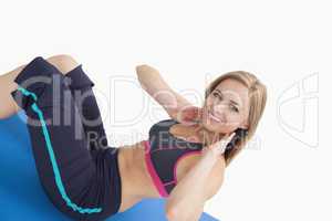 Portrait of happy young woman doing sit-ups on exercise mat