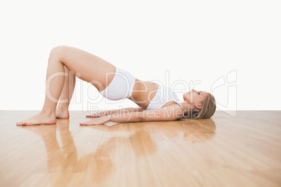 Side view of woman in yoga pose on hardwood floor