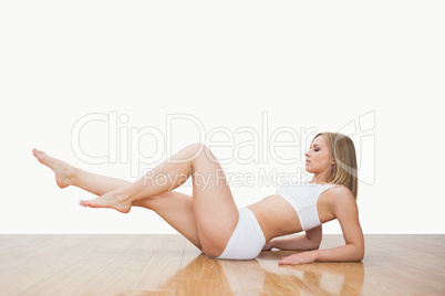 Side view of young  woman in yoga pose on hardwood floor