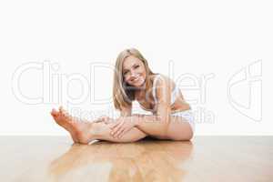 Portrait of young  woman stretching on hardwood floor