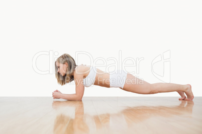 Side view of woman doing push-ups on hardwood floor