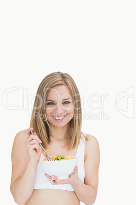 Portrait of young woman with fork and bowl of fruits