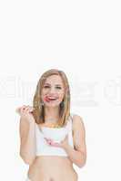 Portrait of happy woman eating from a bowl of fruits