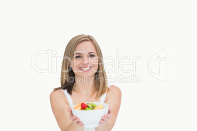 Portrait of young woman offering you bowl of fruits