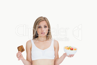 Portrait of young woman holding cookie and fruit bowl