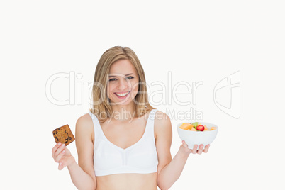 Portrait of happy woman holding cookie and fruit bowl