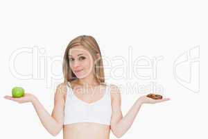 Portrait of young woman holding apple and cookie