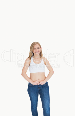 Portrait of slim young woman buttoning jeans