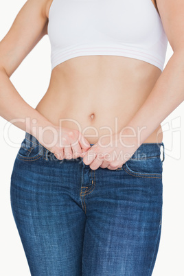 Midsection of slim woman buttoning jeans