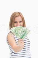 Portrait of happy young woman holding out fanned dollar banknote