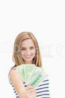 Portrait of happy young woman holding out fanned dollar banknote