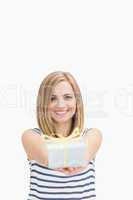 Portrait of cute young woman holding out gift box