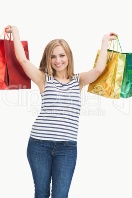 Portrait of cute excited young woman holding up shopping bags