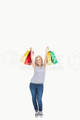 Portrait of cute excited young woman holding up shopping bags